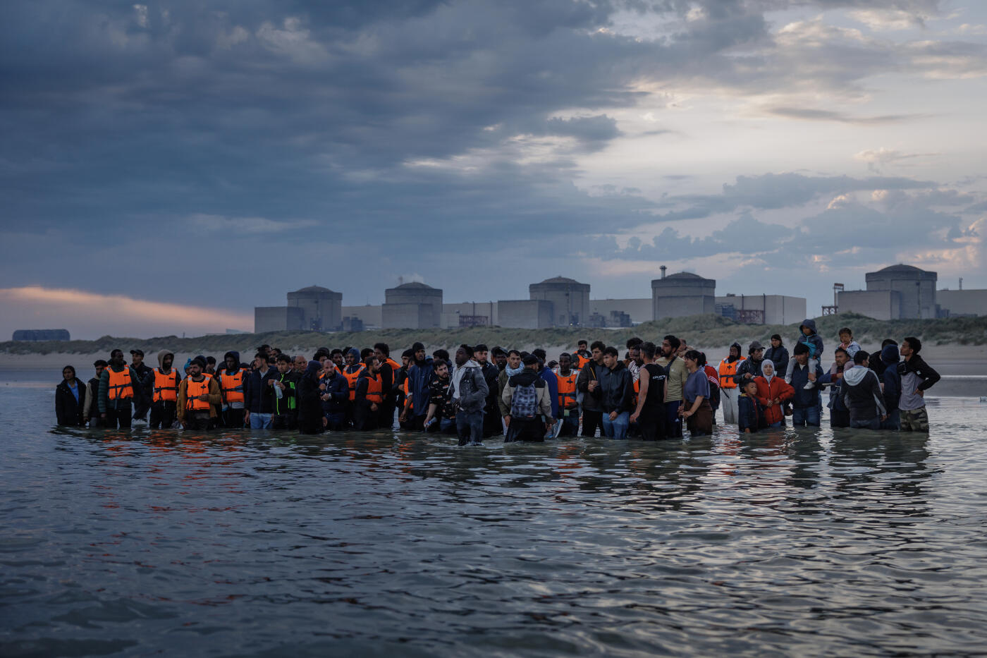 GRAVELINES, FRANCE - AUGUST 12: Migrant families wade into the sea in an attempt to board a small boat on August 12, 2025 in Gravelines, France. More than 50,000 small boat migrants have now crossed the English Channel since Labour came to power last July. Last week the UK and France began implementing the so-called 'one-in, one-out' treaty, which was agreed during French President Emmanuel Macron's state visit last month, in an effort to curb illegal migration across the English Channel. Under the pilot scheme, a proportion of undocumented people arriving to the UK in small boats will be returned to France, in exchange for the same number of legitimate asylum seekers who may have family ties in the UK.  (Photo by Dan Kitwood/Getty Images)