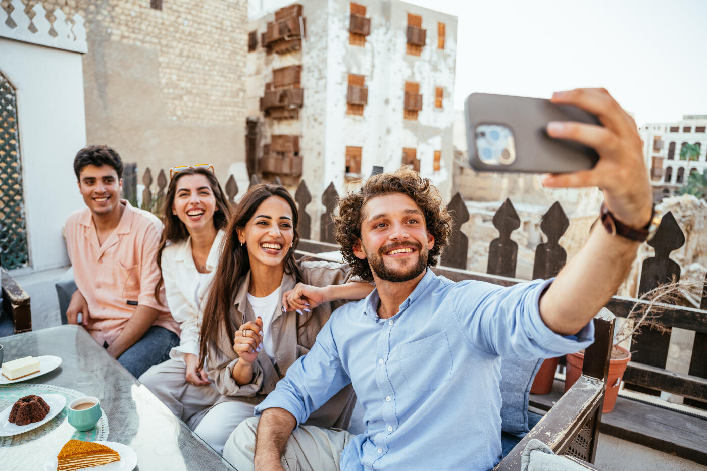 Group of young friends and couples enjoying coffee and sweet food in outdoors restaurant in Middle East old town