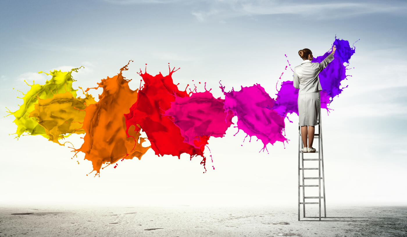 Young woman standing on ladder drawing splashes with finger