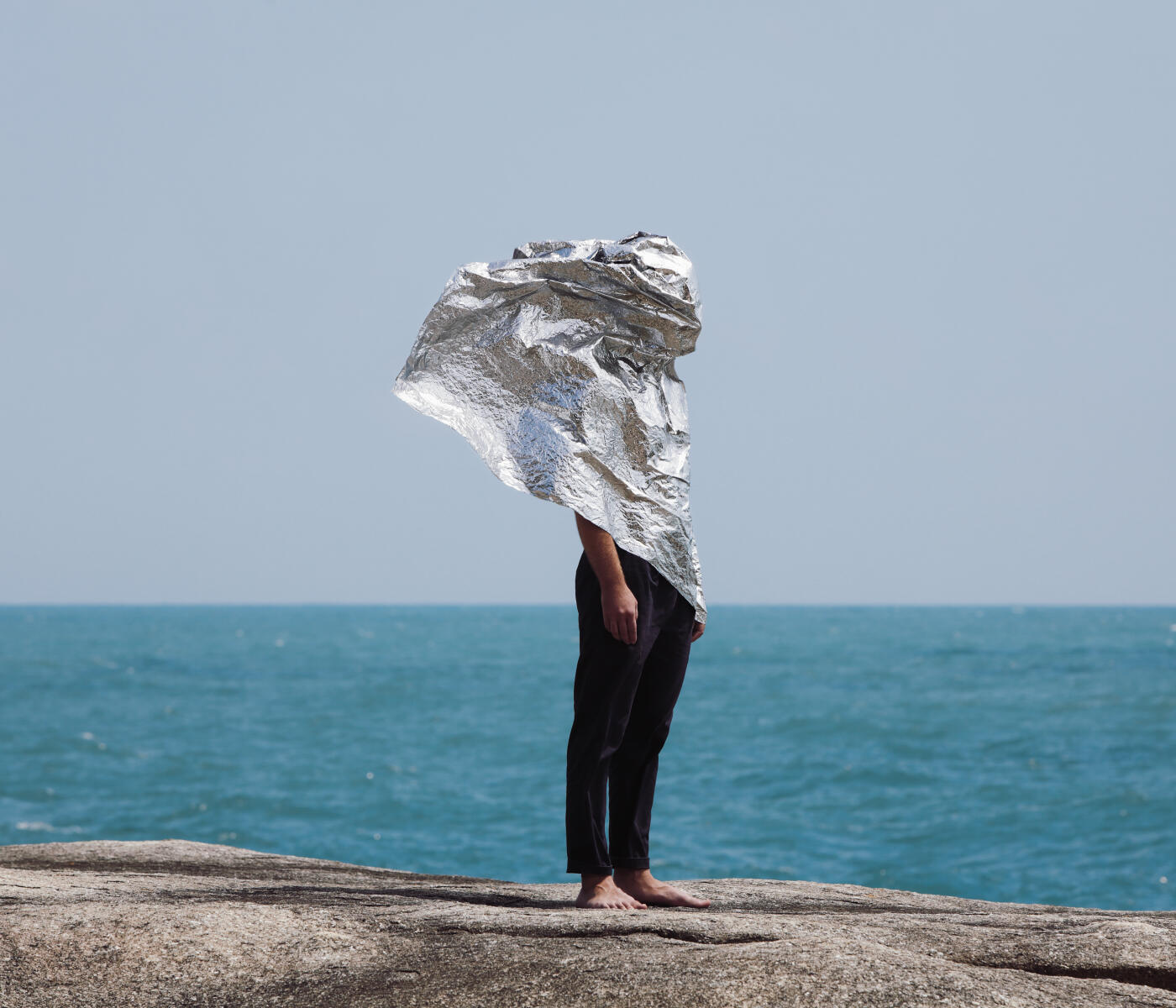Man covered with silver foil against the sea