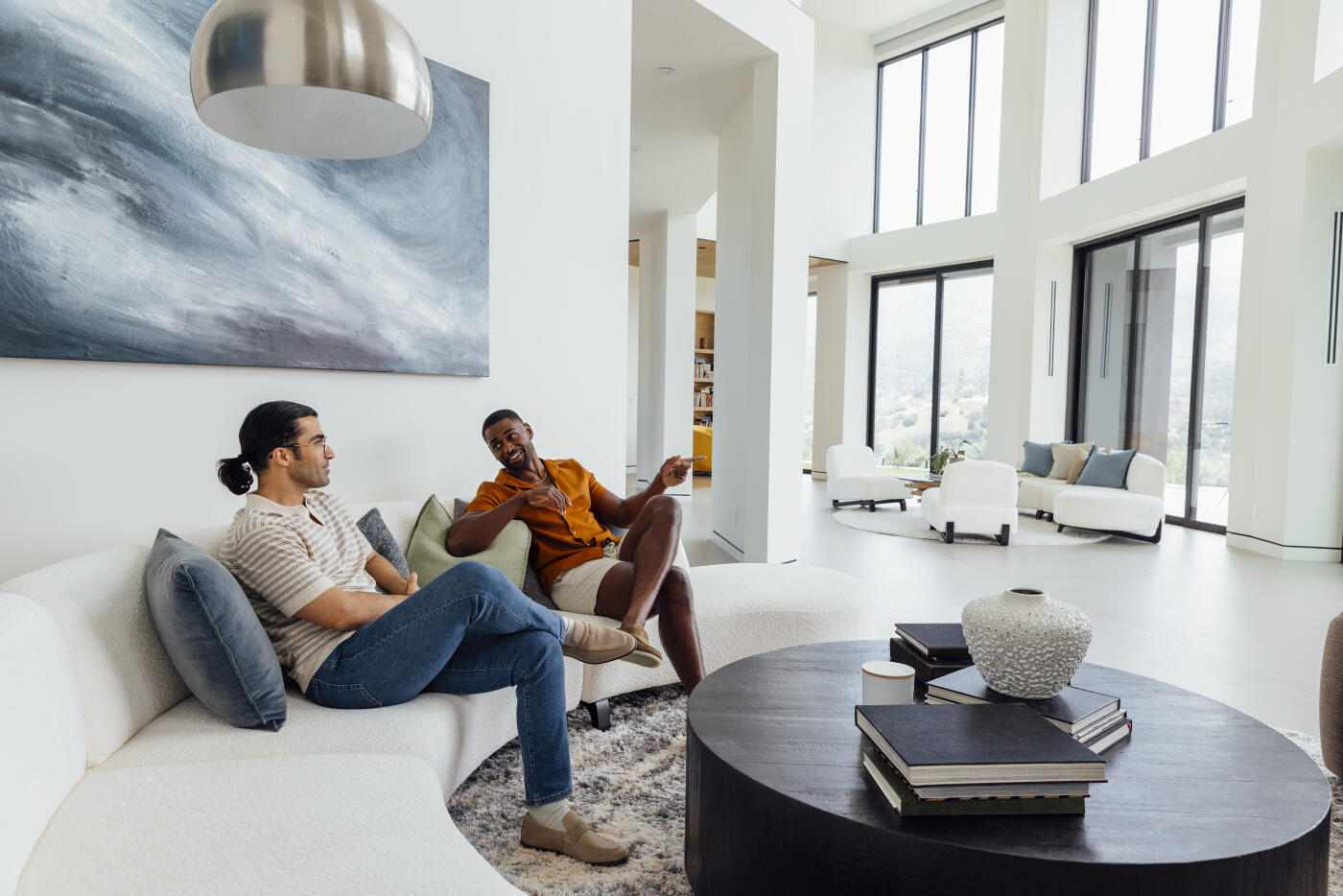 Male friends relaxing and talking together on a sofa in a modern luxury living room