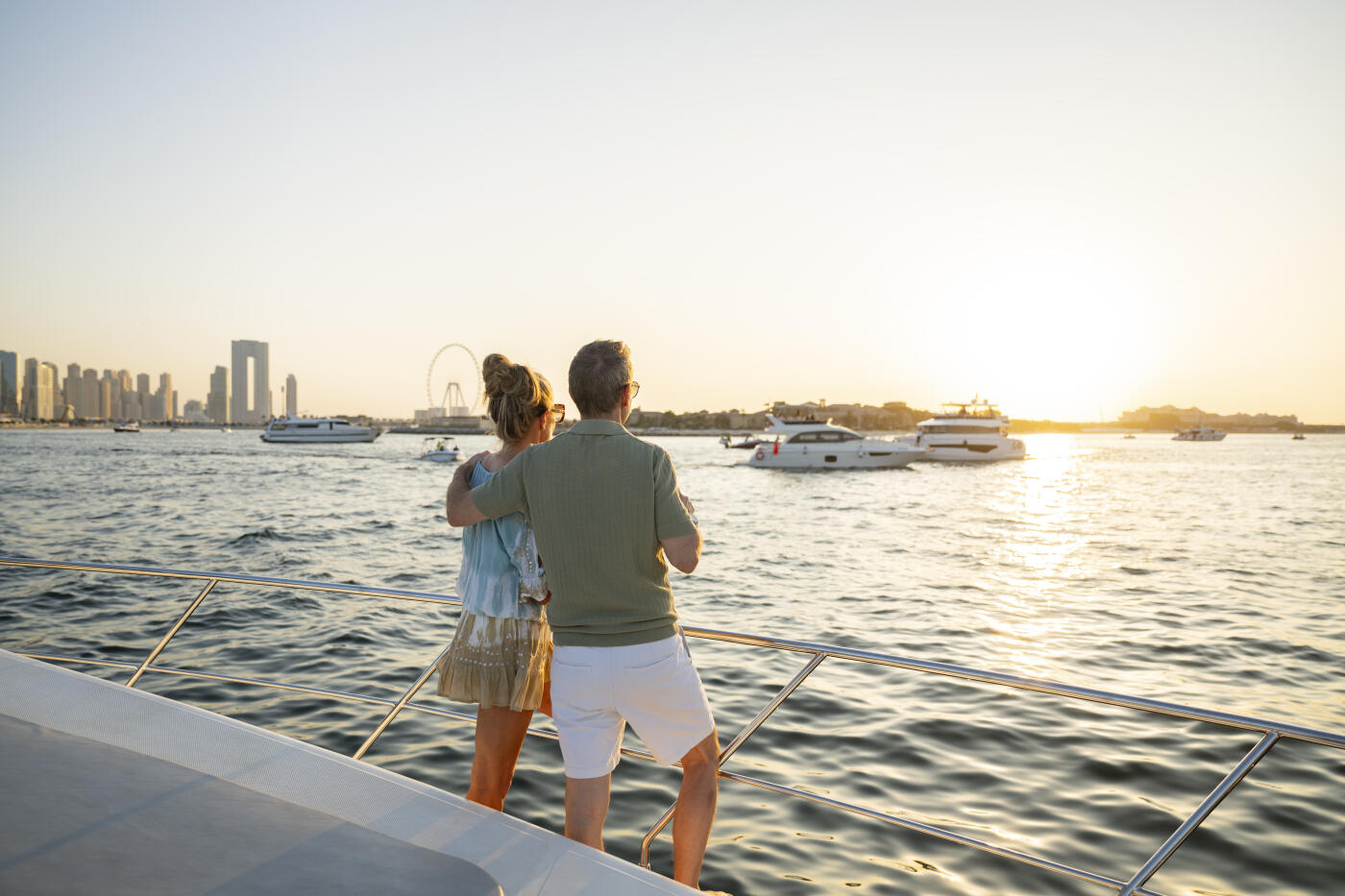 Couple in their 50s vacation, man with arm around woman, enjoying the tranquility of sunset