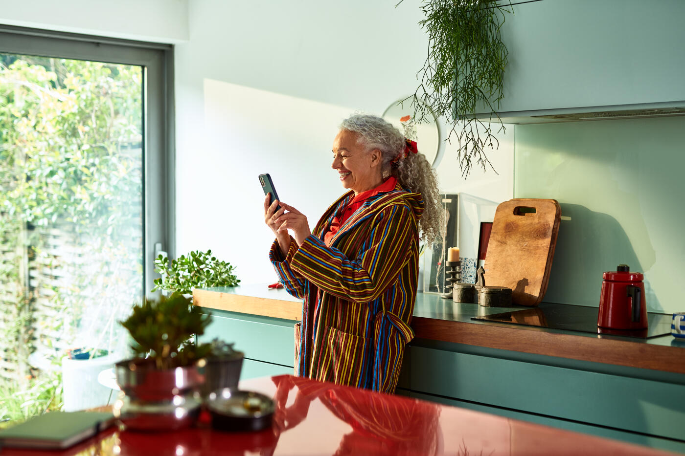 Senior woman using speaker phone at home, cheerful, communication, texting, wireless technology