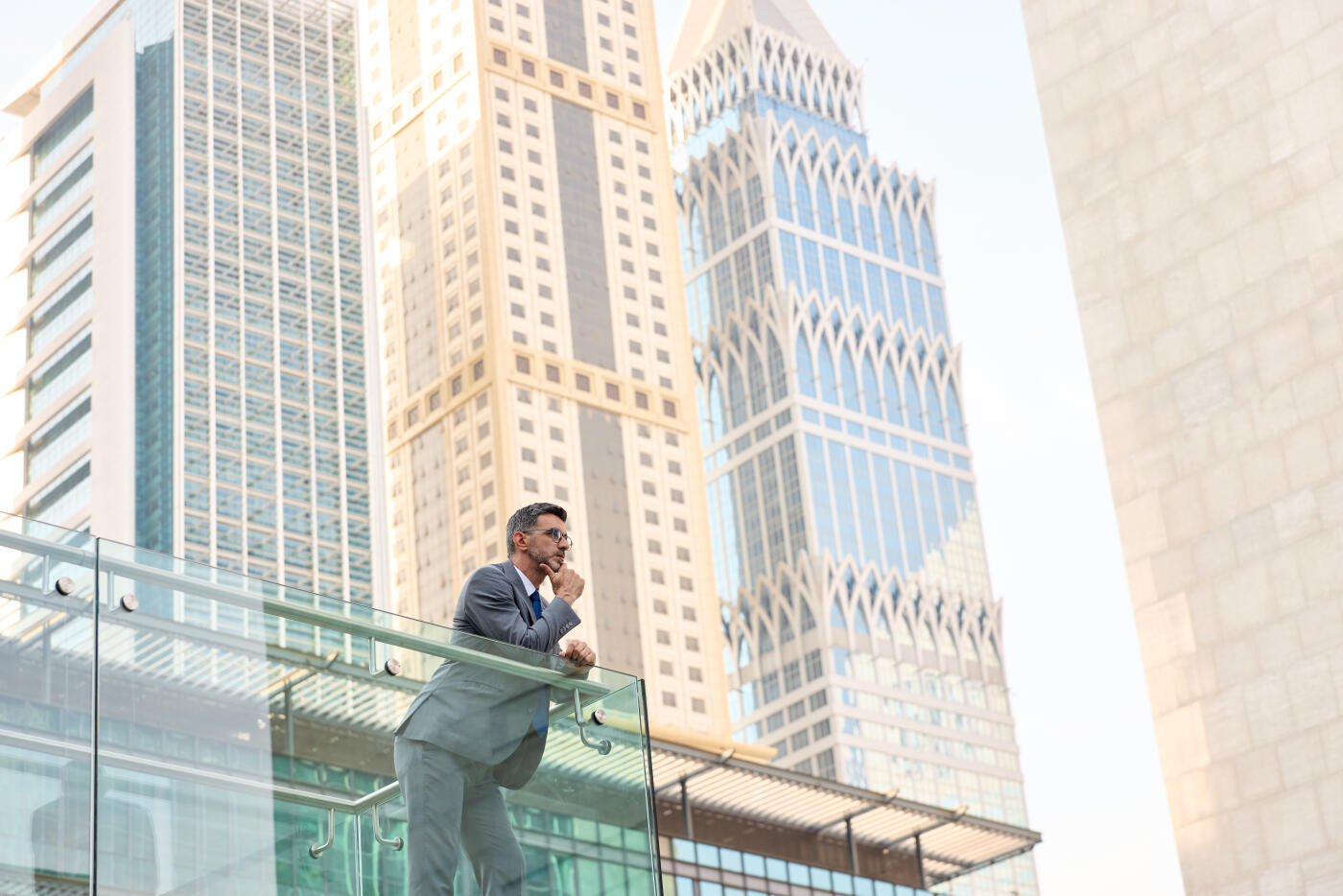 businessman rests his chin in his hand and gazes into the distance, taking a moment outside the office building.