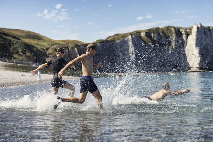 Three teenagers enjoying an invigorating run into the sea on Etretat beach.