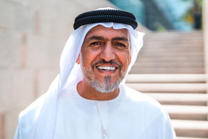 Mature Emirati Businessman Smiling in Traditional Kandura and Headscarf