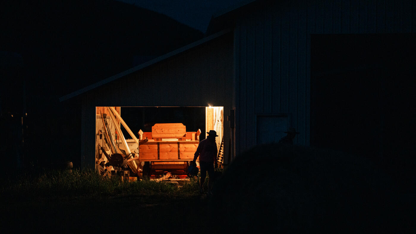 Before sunrise, a farmer gathers equipment and begins the day's work in a dimly lit barn on a quiet Wyoming ranch.