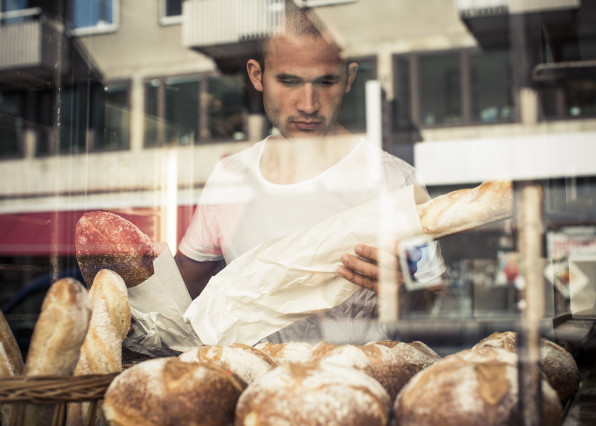 View of mid adult male owner working at bakery through display cabinet