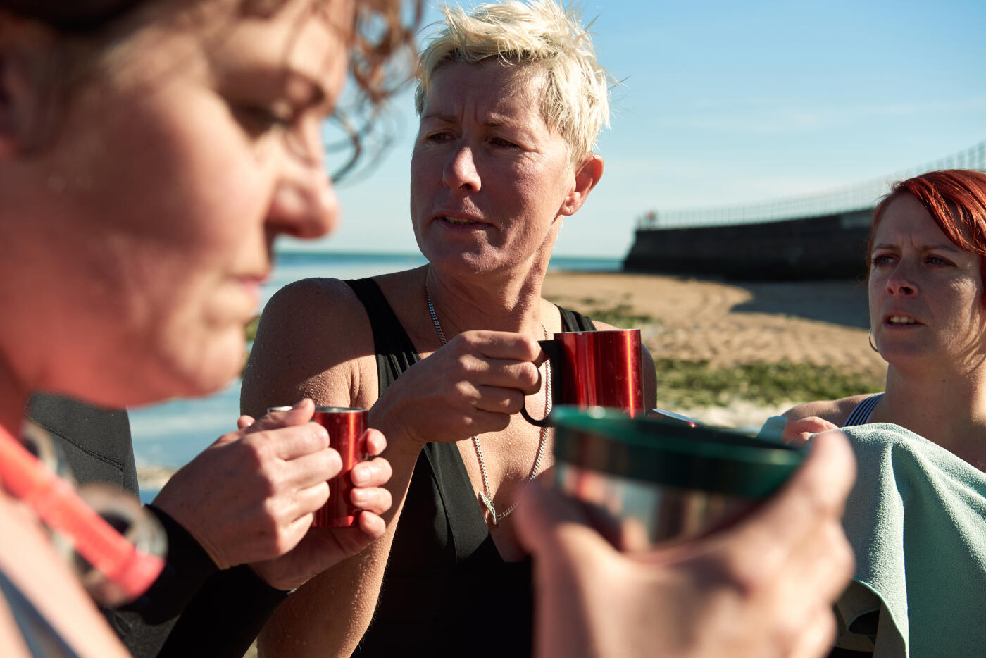 Group of women who regularly swim in the sea pool, enjoy a hot drink after a bracing swim at the Walpole Bay Tidal Pool, Margate, Kent, United Kingdom.