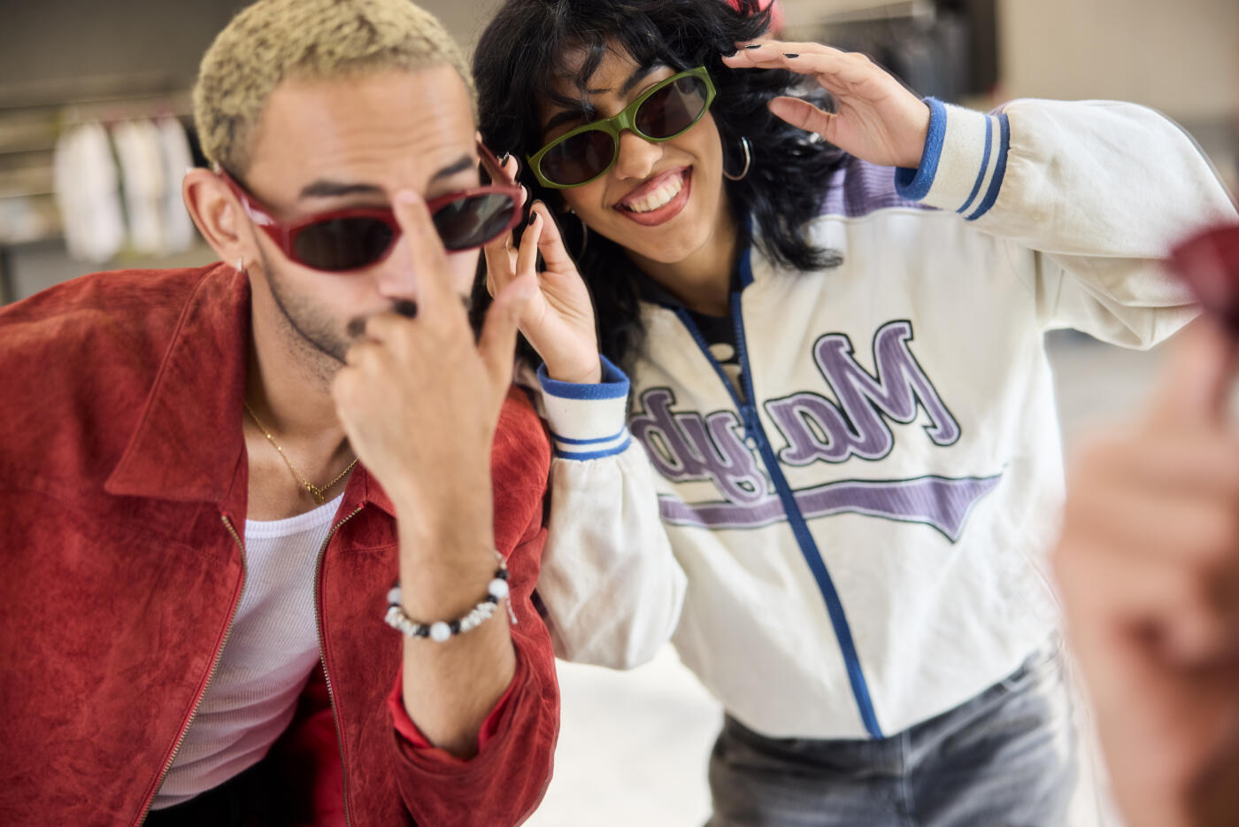 Two people with sunglasses look at their reflection in a mirror.