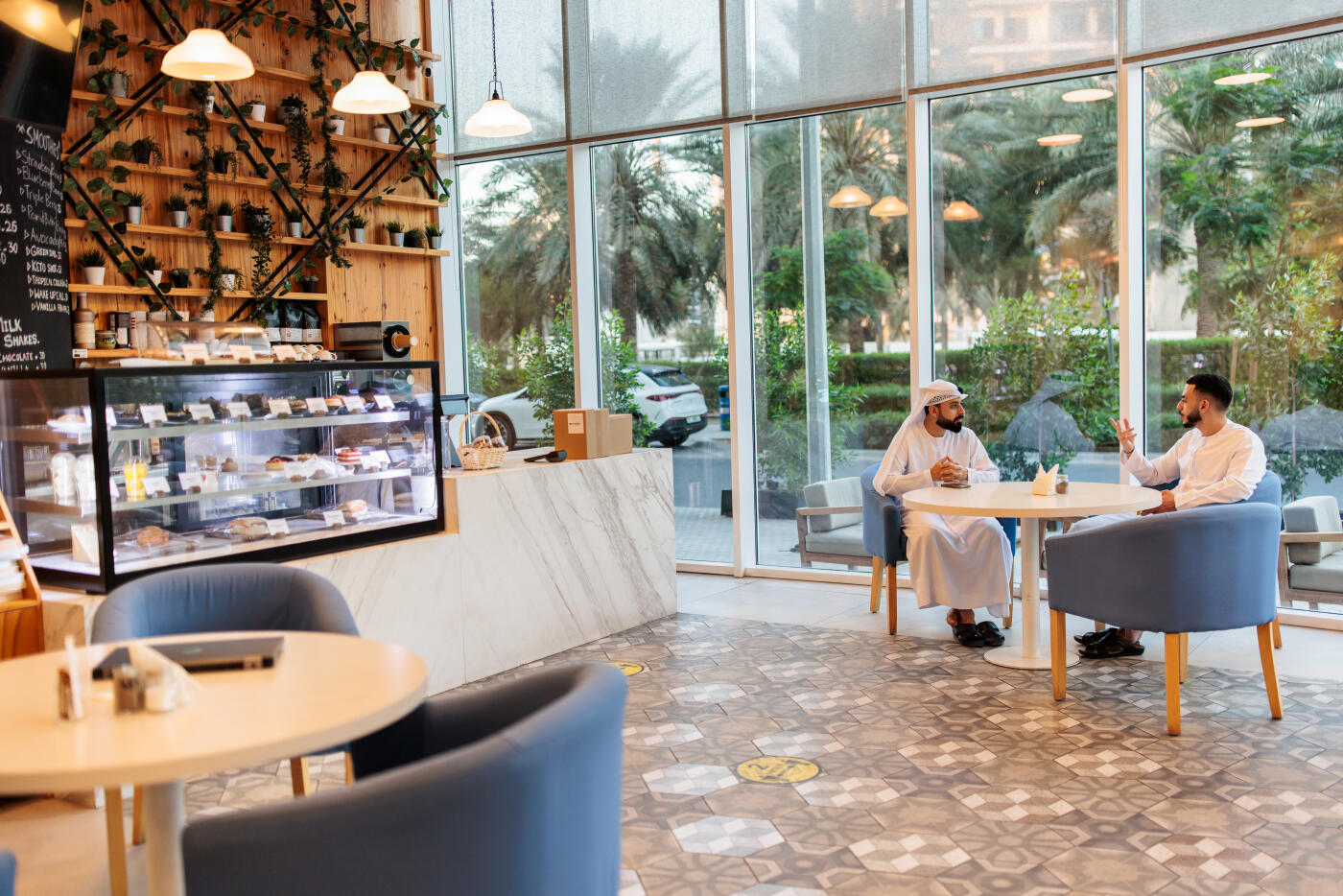 Muslim man in kandura and his casually dressed friend enjoying a friendly chat at a chic Dubai café
