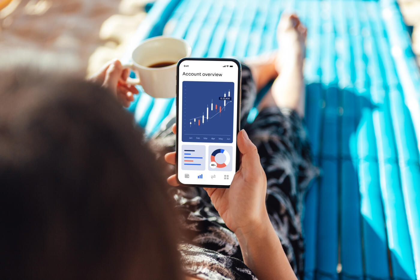 Over the shoulder view of young woman looking at financial data on smartphone while enjoying beach holiday. Personal banking and financial investment concept.