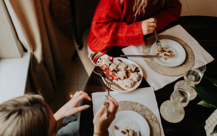 Top down image of people eating a festive dessert of sweet mince pies and white wine