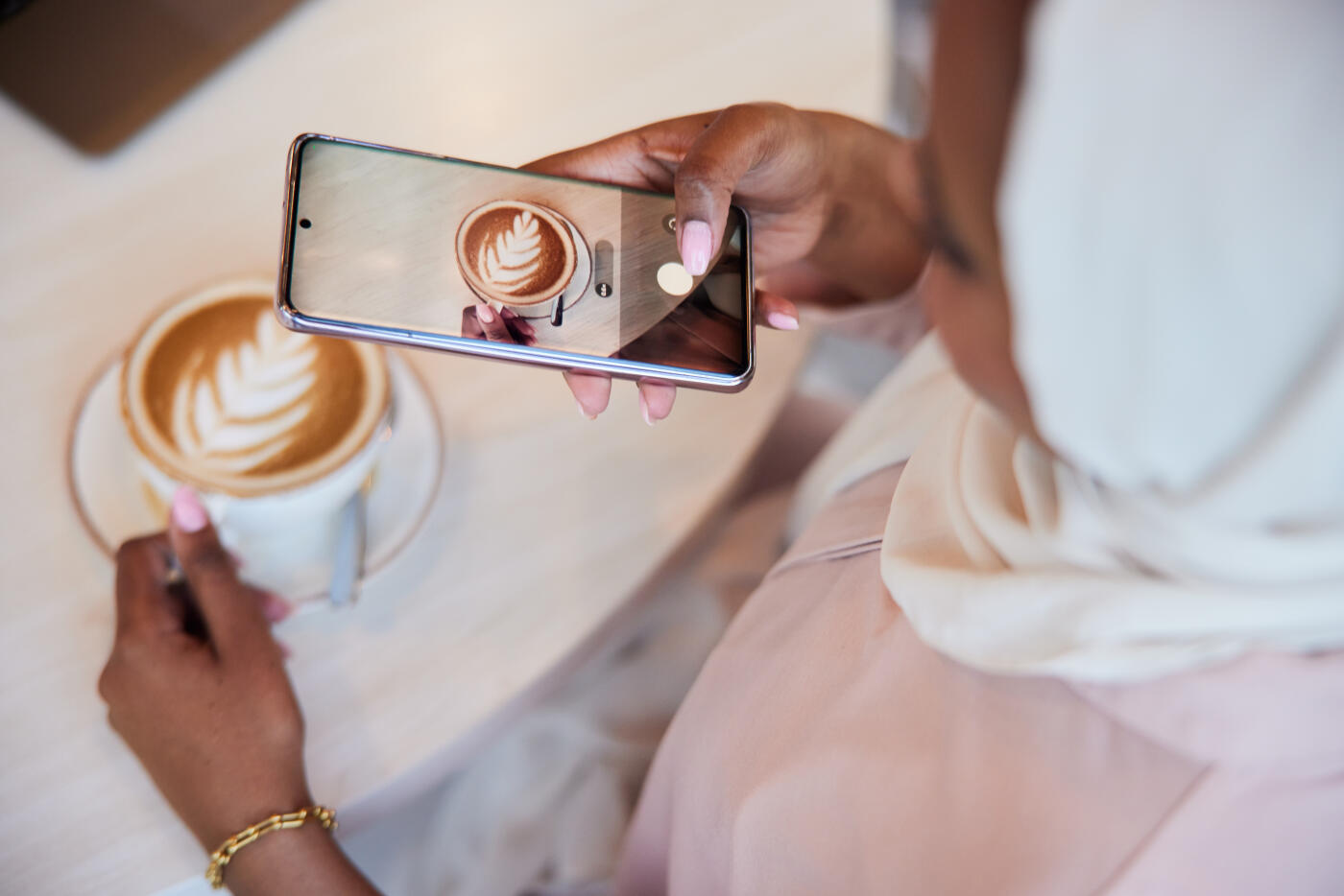 On the phone screen, a close-up view reveals a photo of a cappuccino