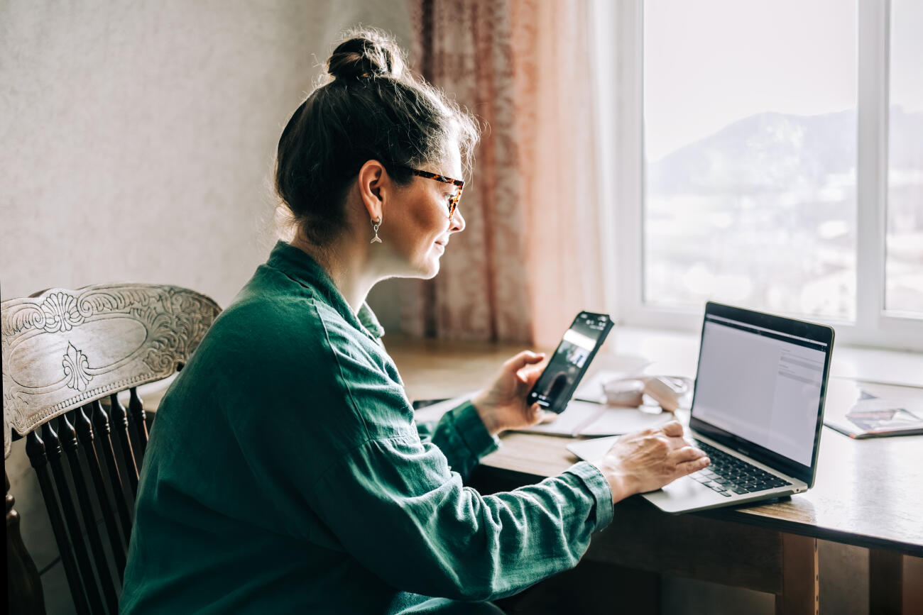 Mature woman using laptop and smartphone at home