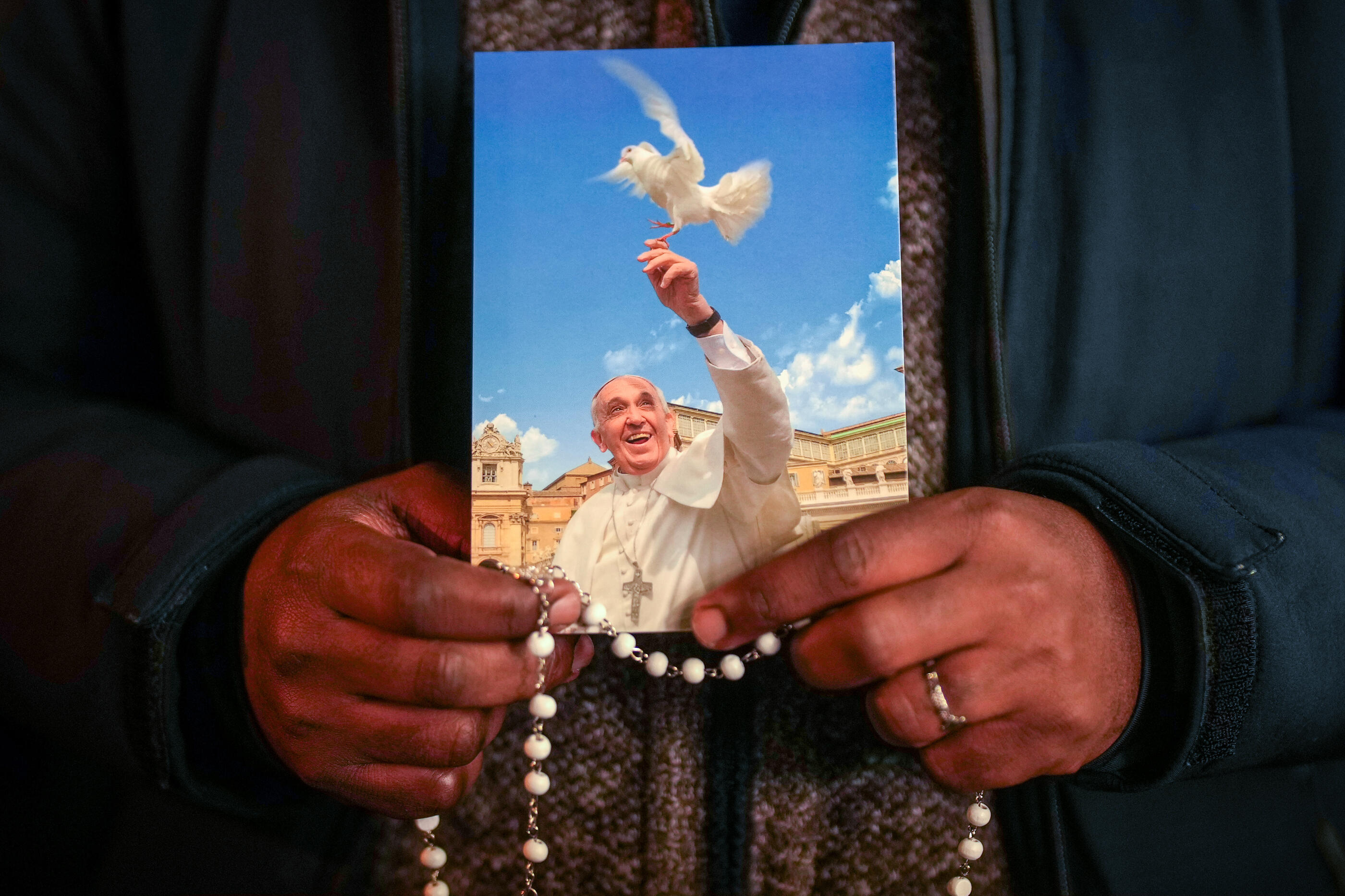 VATICAN CITY, VATICAN - MARCH 07: A priest holds a photograph of Pope Francis as faithful pray during the nightly rosary prayer service in St Peter's Square on March 6, 2025 in Vatican City, Italy.  Pope Francis was hospitalised in Rome on February 14 with bronchitis, and later developed pneumonia in both his lungs.  (Photo by Christopher Furlong/Getty Images)