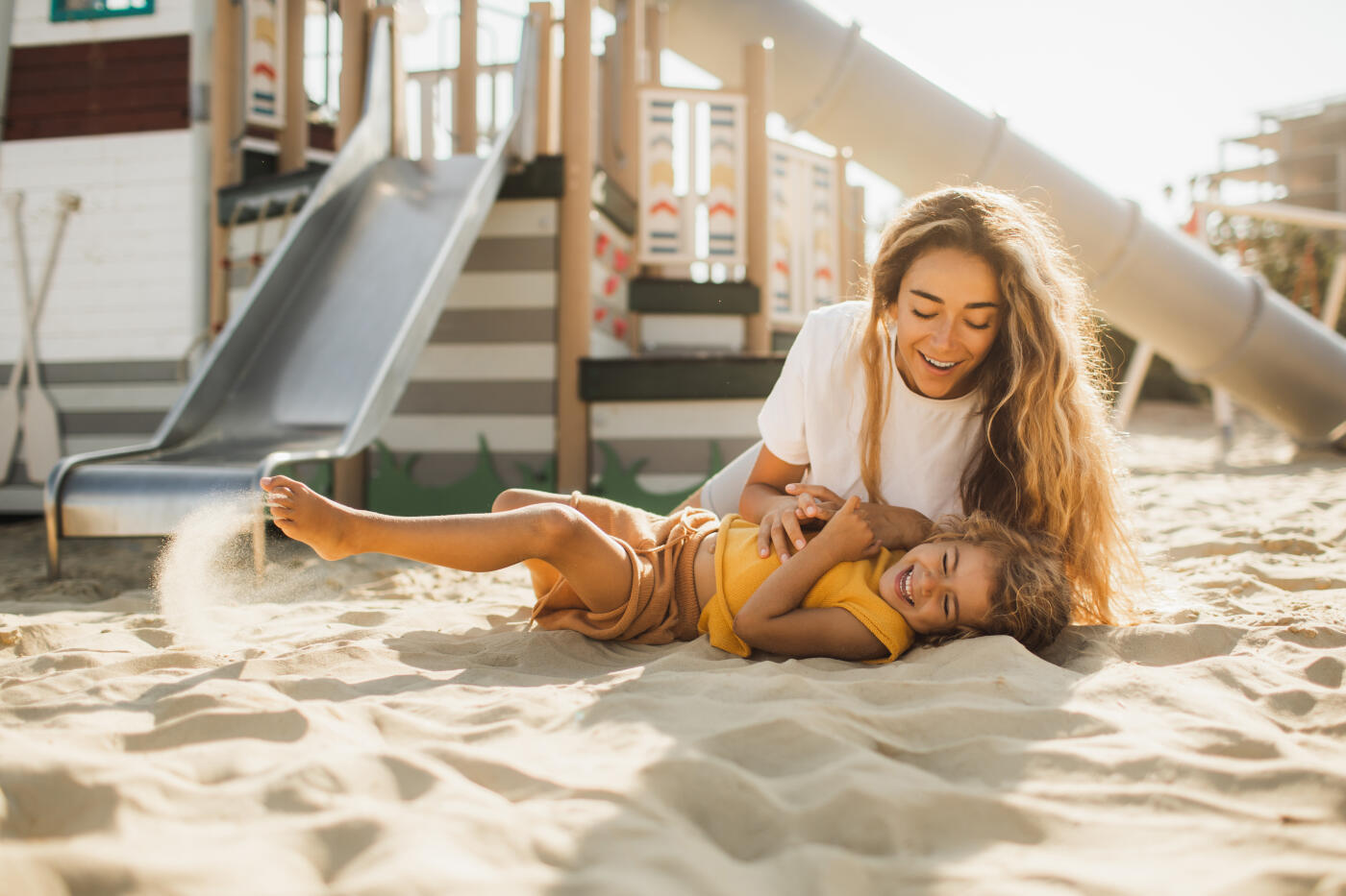 Harmony in family and sustainable parenting, mother spending time together with daughter.  Both laughing and smiling. Comfortable and trendy urban environment for children on seaside in UAE. Kids entertainment park.