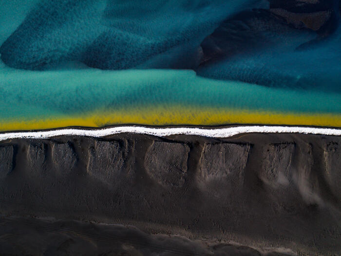 Drone shot showing a black sand beach at the edge of braided river, Iceland