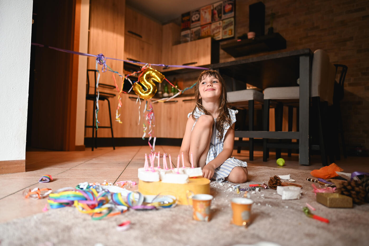 Child having birthday tea party in kitchen.