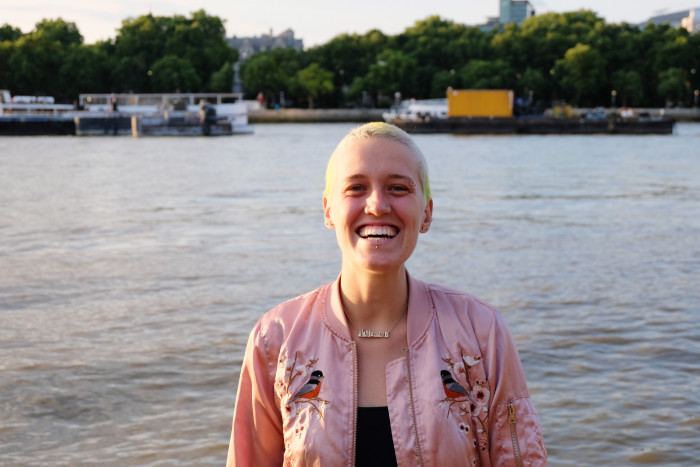A waist up portrait young woman along the Thames in London during a sunset.