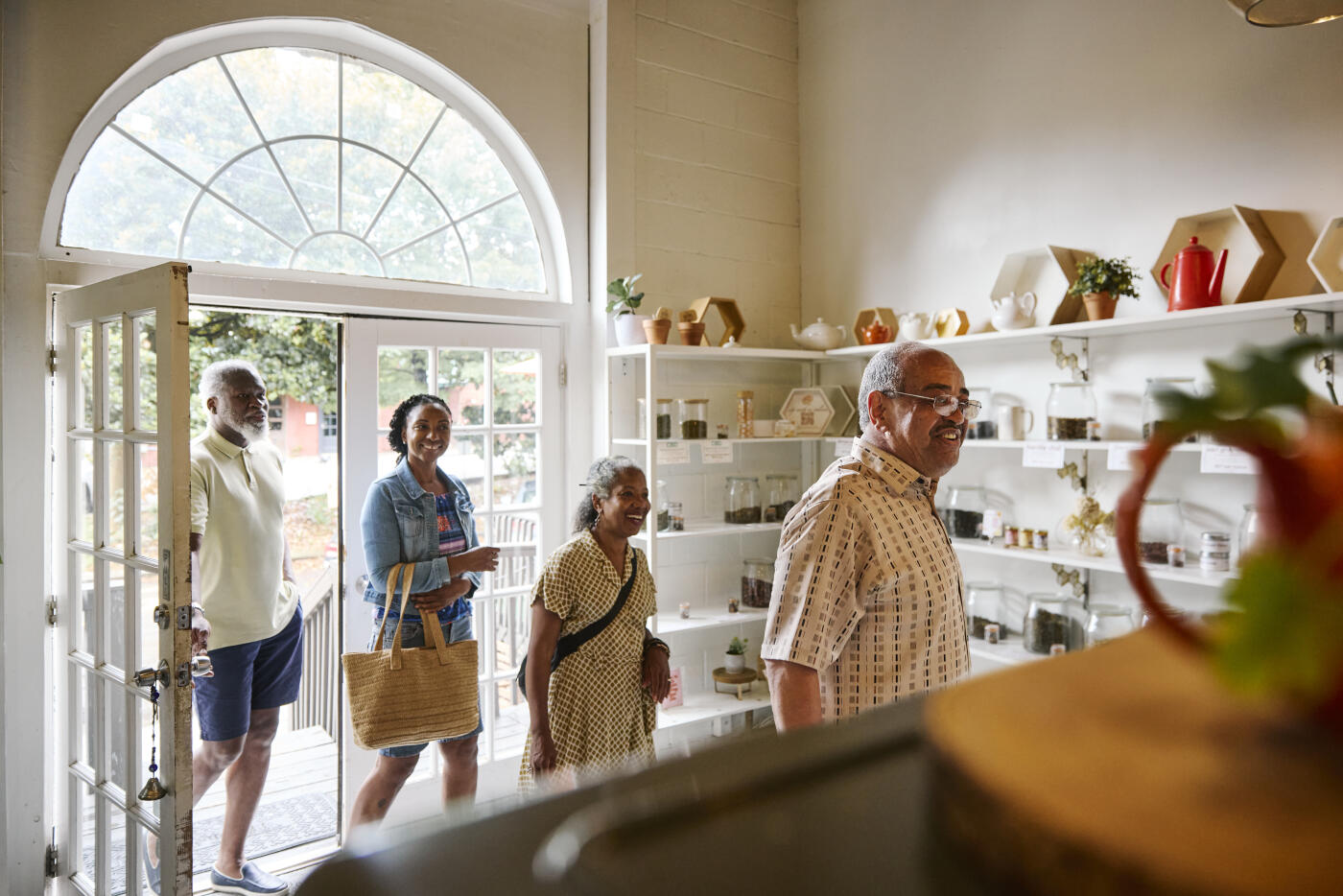 A group of male and female friends are entering a retail tea shop and café, intending to enjoy an afternoon tea and browse the merchandise.