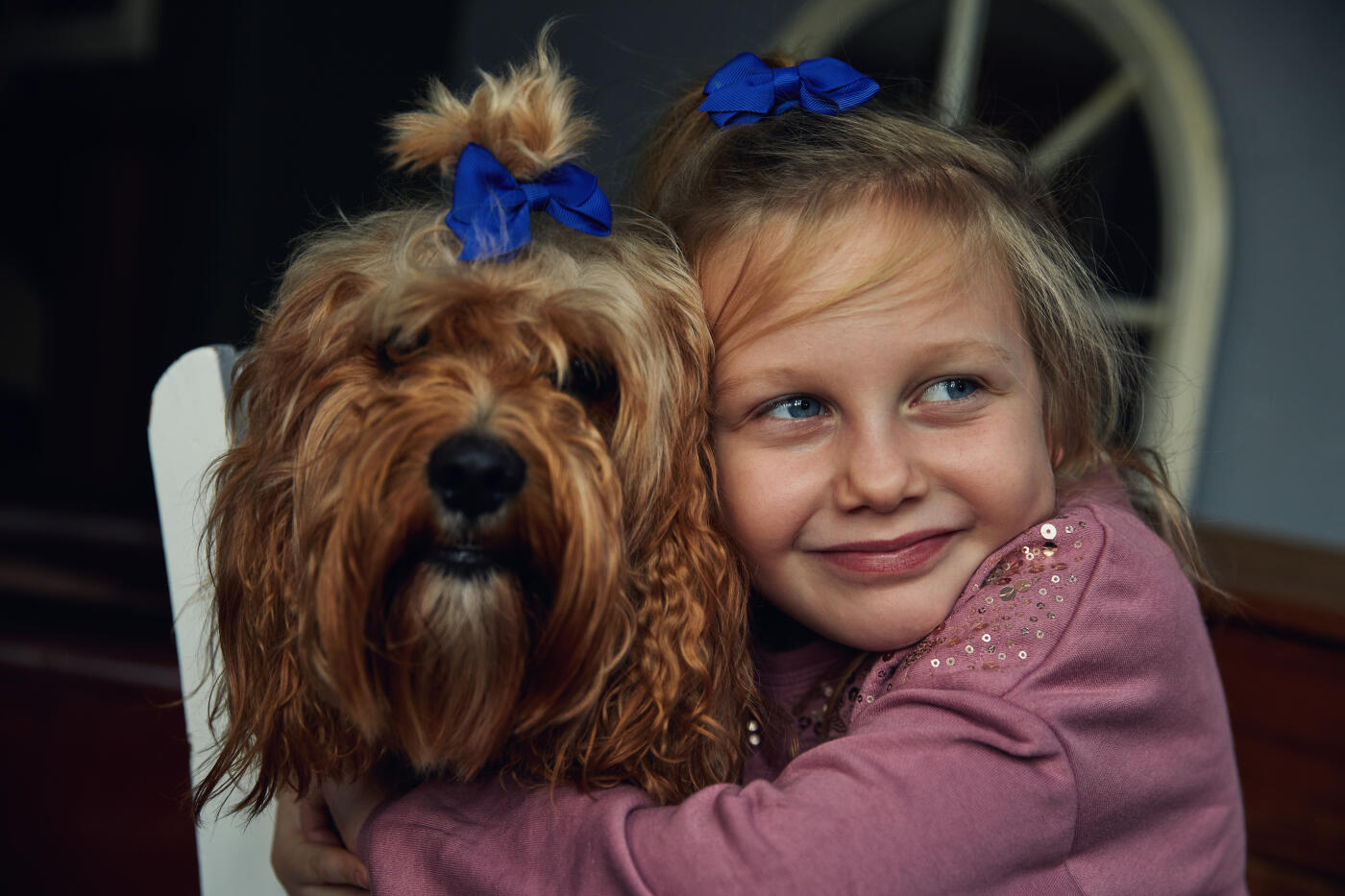 Happy smiling little girl with her pet dog, with matching hair styles wearing blue bows in their hair