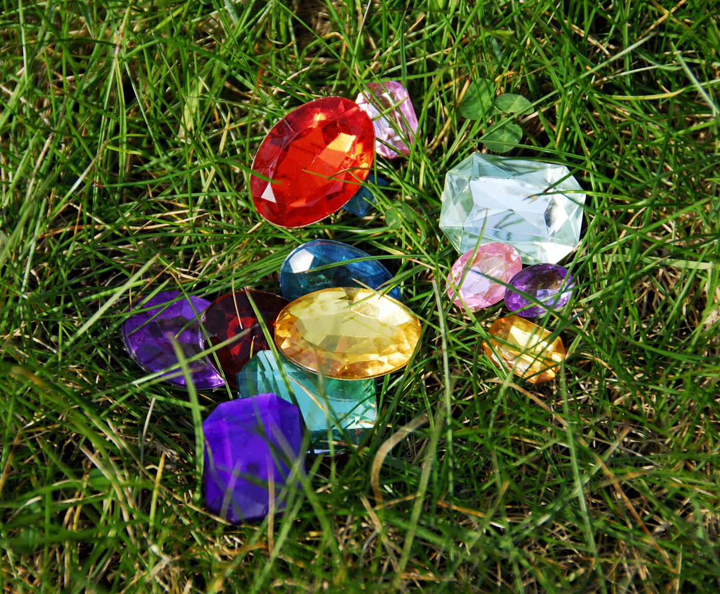 Abstract image  of coloured jewels in green grass to create a magical ethereal image.