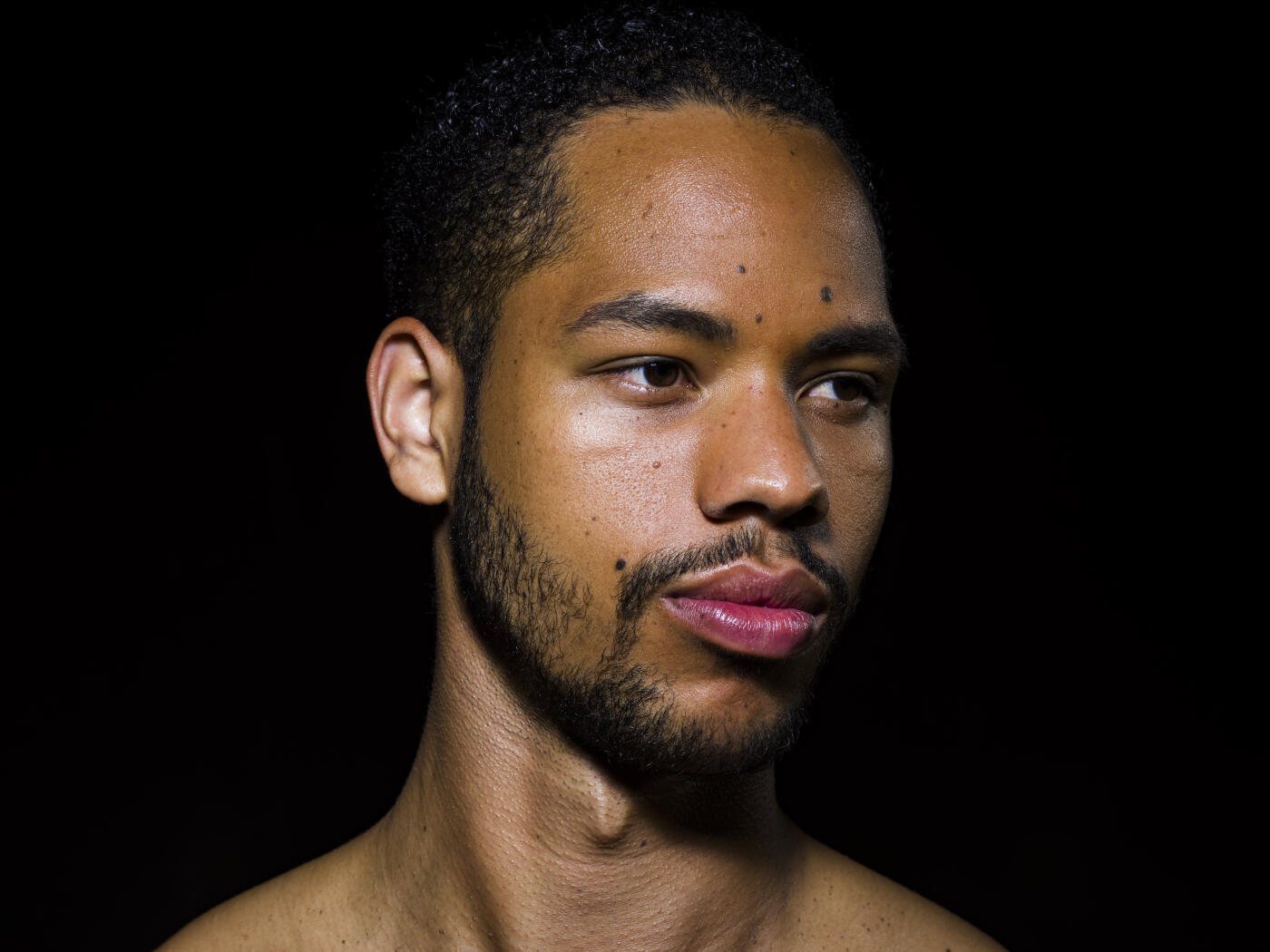 Studio portrait handsome, thoughtful young man with beard looking away on black background