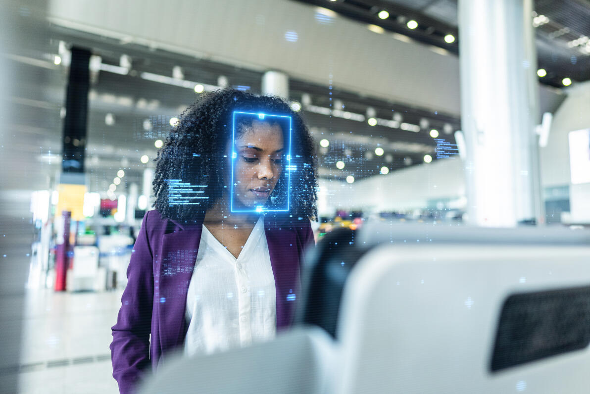 Focused young businesswoman standing at an airport check-in kiosk, with facial recognition technology digitally scanning her face, highlighting advanced security, innovation, and efficiency in modern travel.