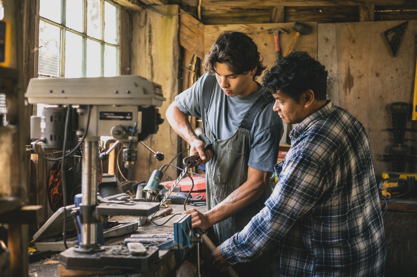 Father teaching adult son in farm workshop