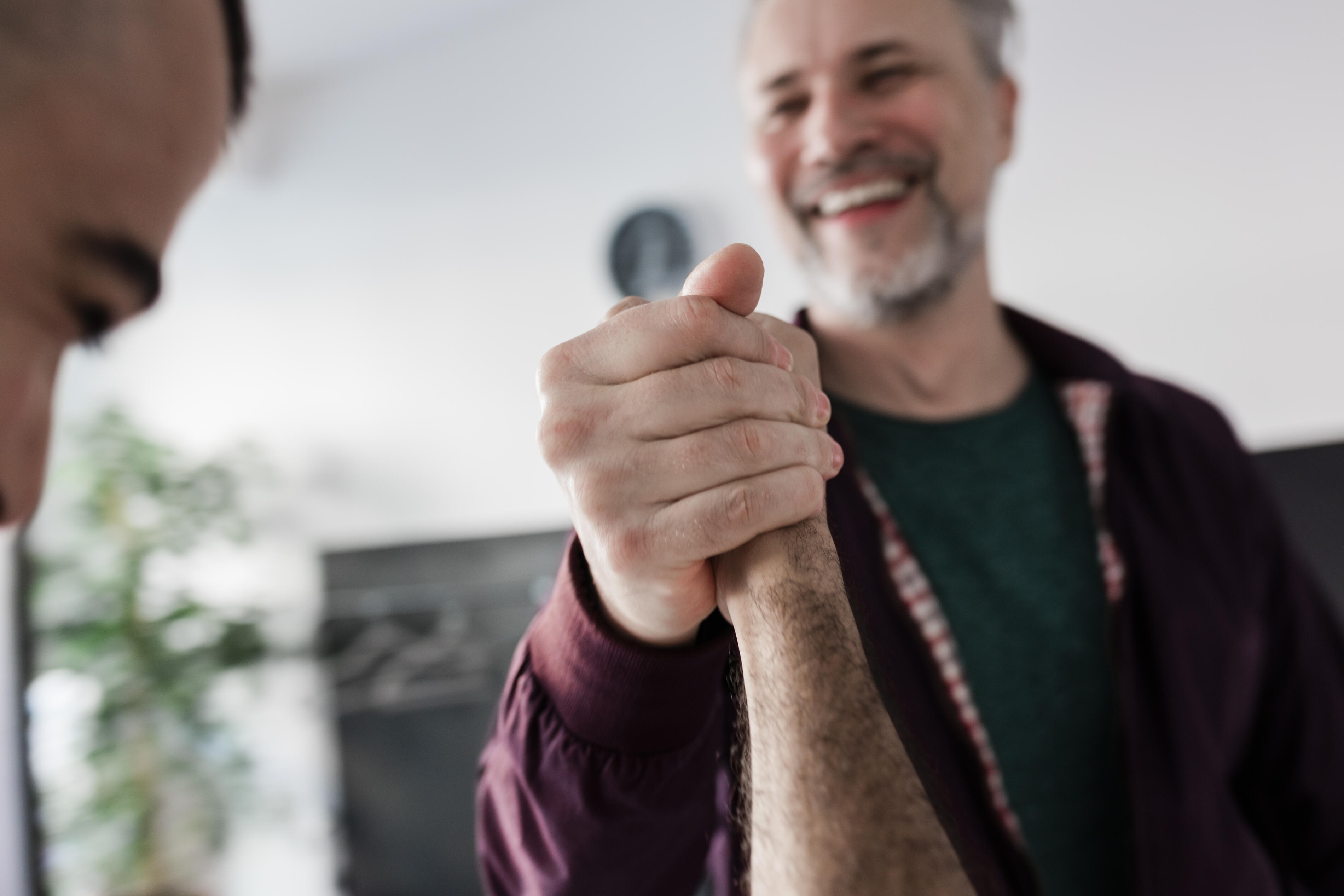 Fester Händedruck eines Kunden und Trainers im Fitnessstudio