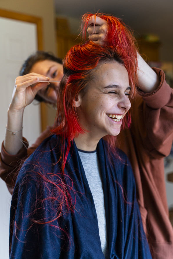 Older sister cutting her younger sister's hair at home, and both of them having fun.
