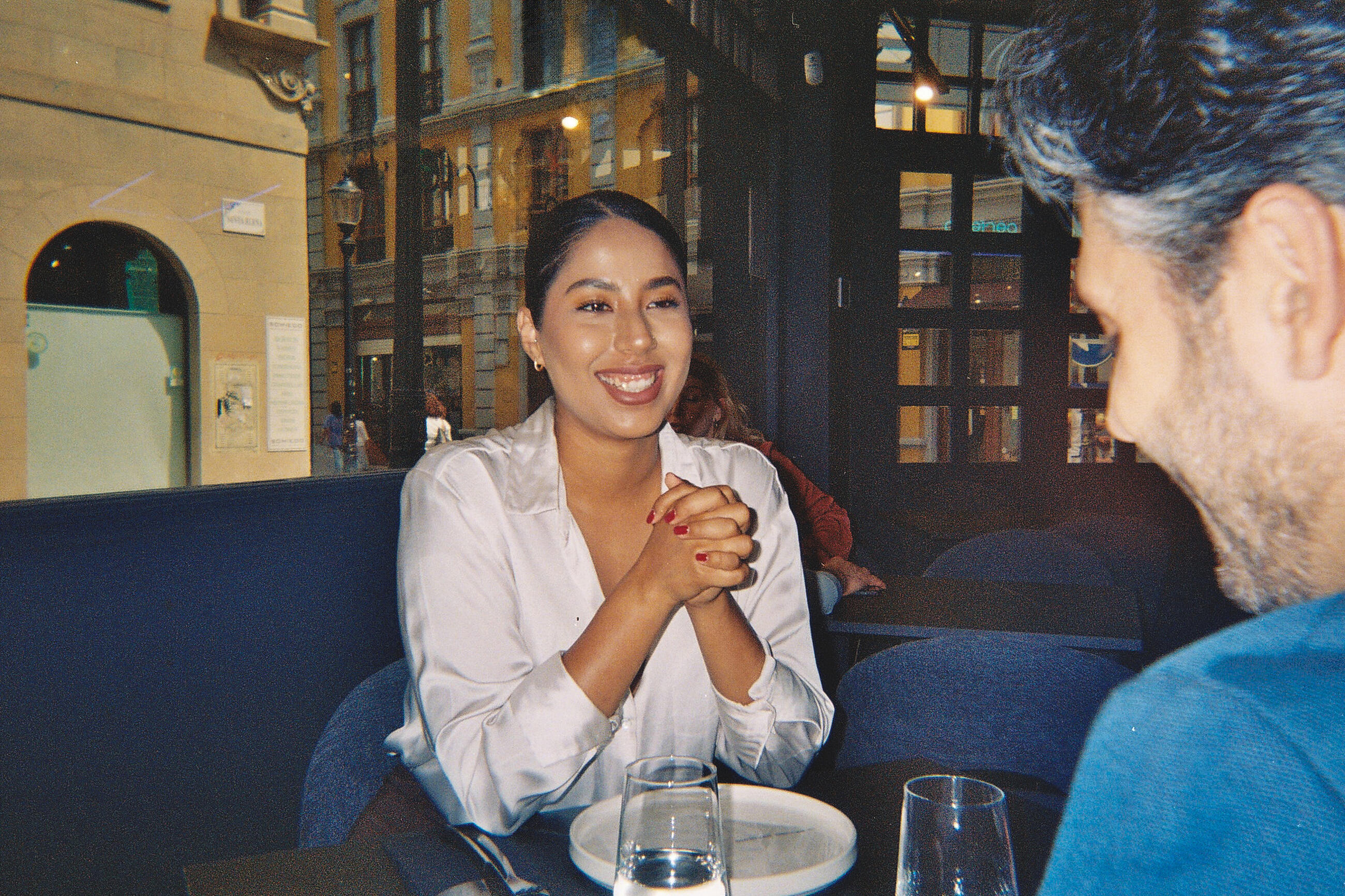 Woman laughing during dinner date at restaurant showing happiness and fun while having conversation