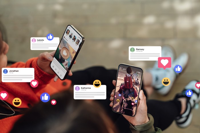 Closeup of two friends commenting and giving likes on social media platform via smartphone