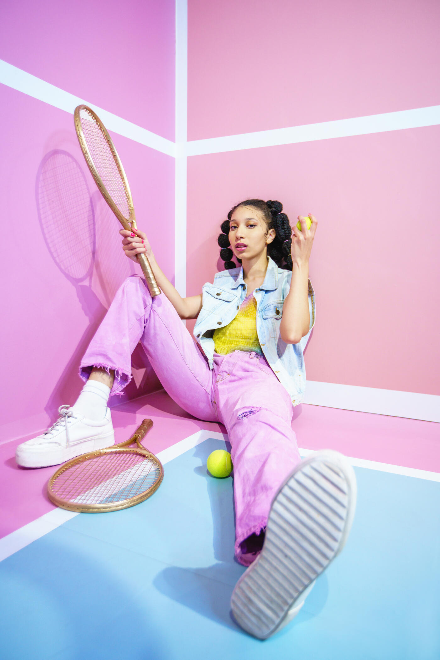 Vertical full length view of tennis player with pastel urban clothes hitting the ball in the air. People and sport concept