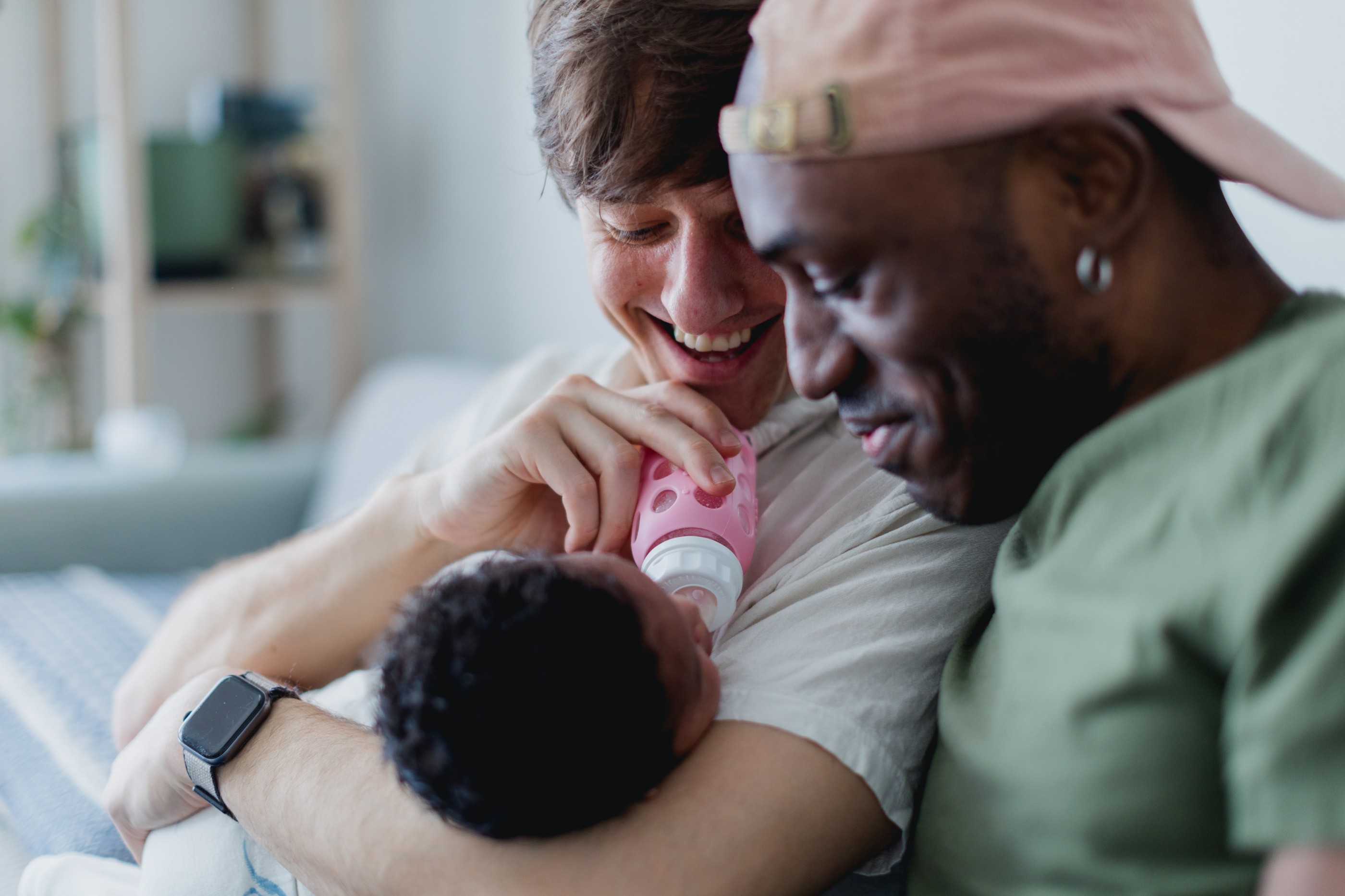 Two loving dads giving their baby a bottle and relaxing at home.