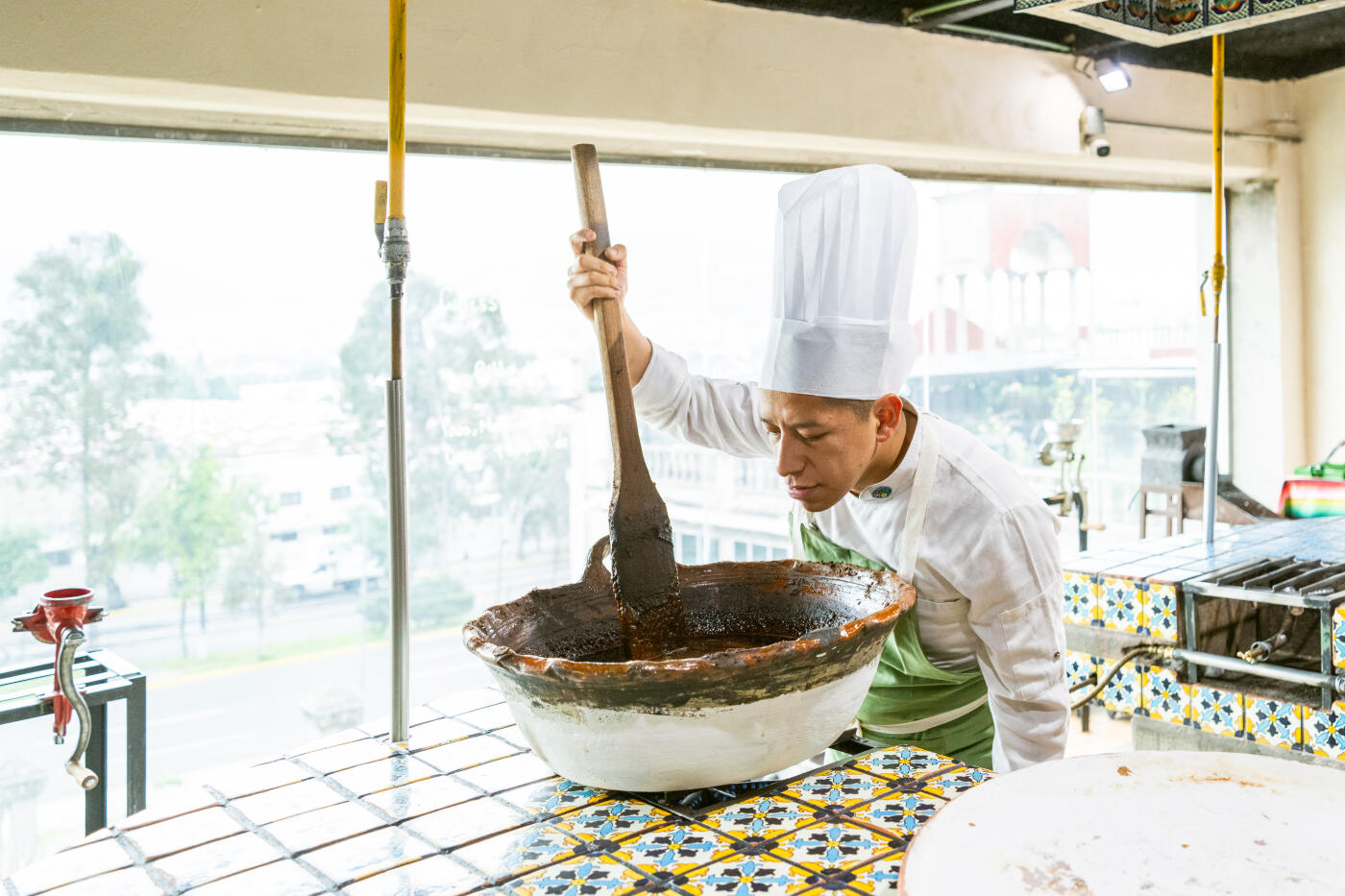 Chef cooking mole in a large terracota casserole