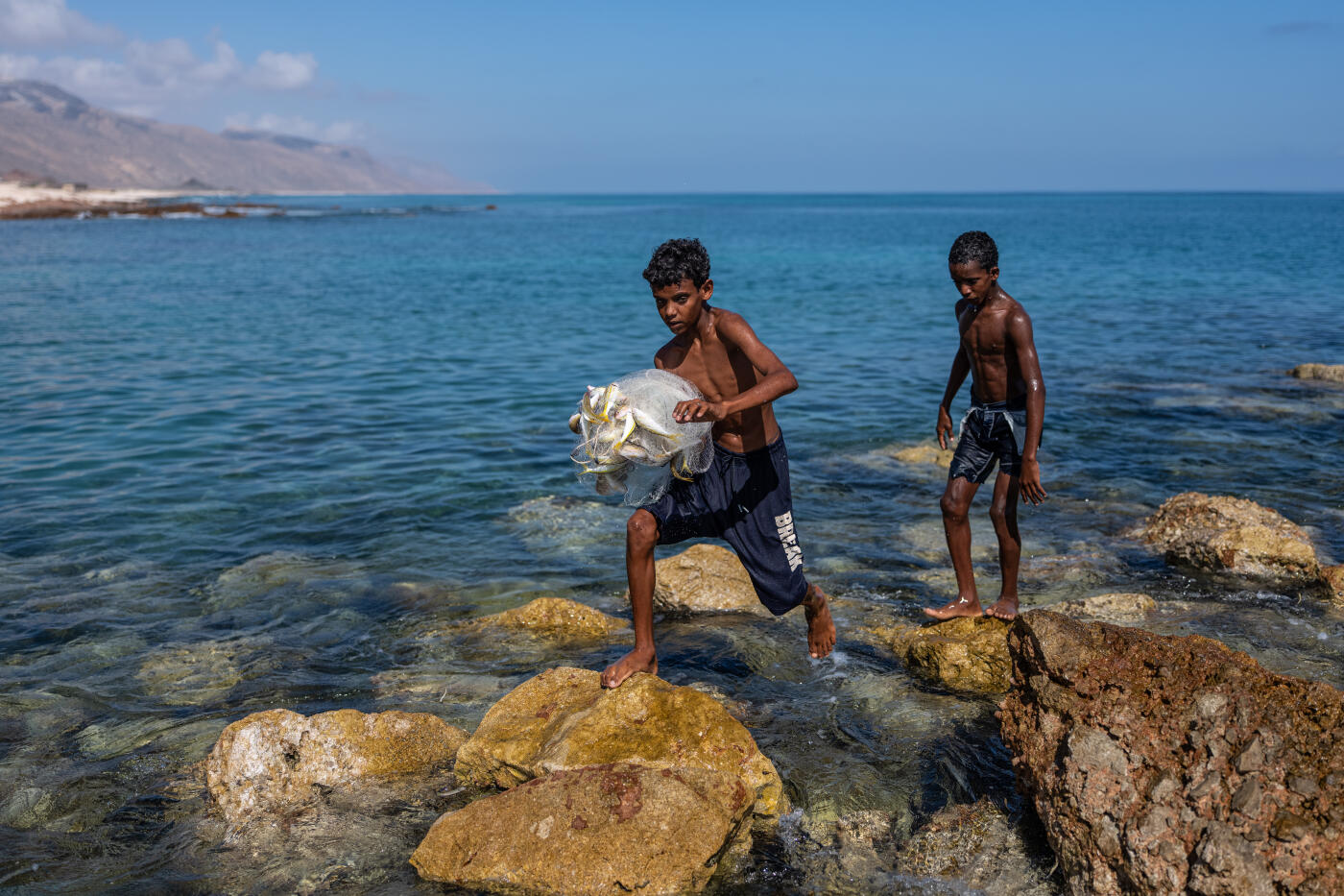 SOCOTRA ISLAND, YEMEN - OCTOBER 12: A boy carries a fishing net with a recent catch back to the beach on October 12, 2025 in Socotra, Yemen. Socotra island, sometimes referred to as the "Galapagos Islands" of the Indian Ocean, lies about 150 miles off the coast of the Horn of Africa and is home to 825 plant species, more than a third of which are only found here. Among them are the otherworldly dragon's blood tree, bottle trees and 11 species of frankincense, 4 of which were classified as critically endangered in March of this year. The intensifying tropical cyclones in this part of the Indian Ocean, fuelled by climate change, has put the island's unique ecosystem at risk. Meanwhile, Yemen's civil war - as well as the region-destabilizing attacks on commercial vessels in the Red Sea - have complicated conservation efforts. (Photo by Carl Court/Getty Images)