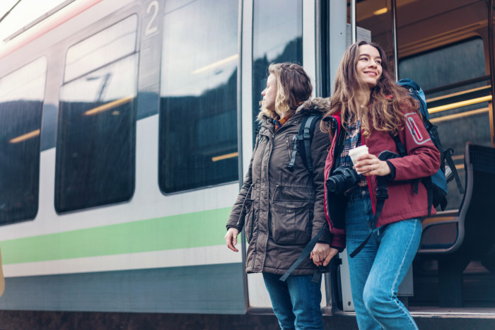Female hikers getting off the train and looking around the railway platform