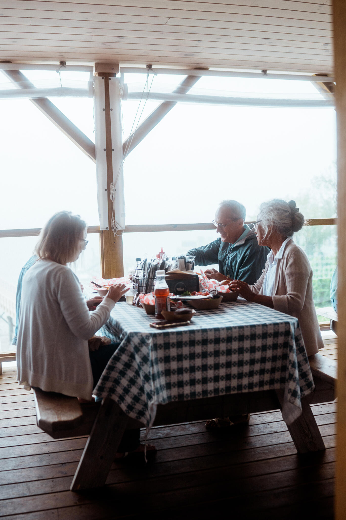 A group of senior friends share a meal at a picnic table in a casual lobster shack on an island off the coast of Portland, Maine.