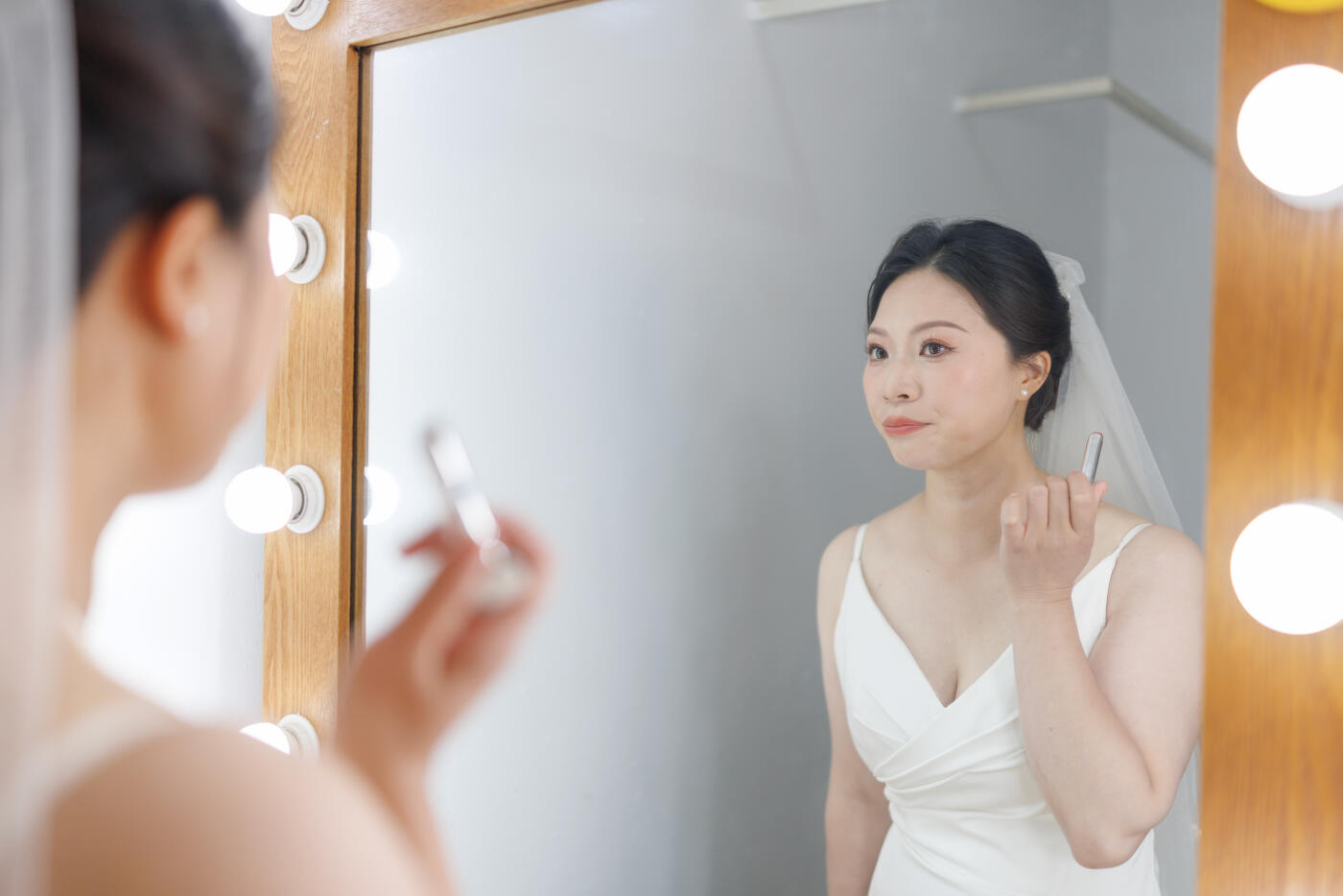 A Chinese woman in her thirties is putting on makeup on her wedding morning and checking her makeup in the mirror