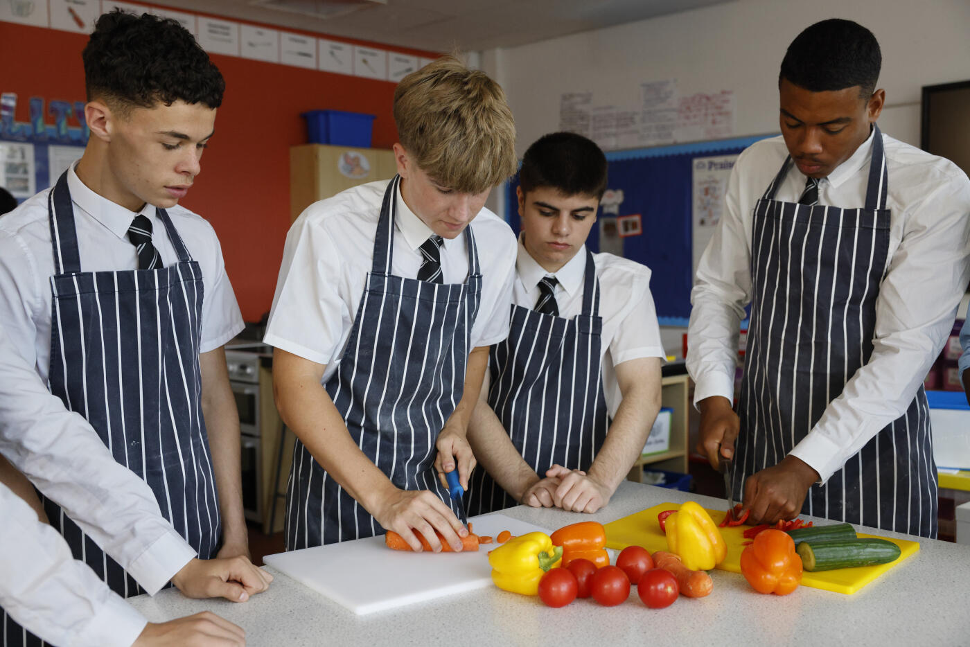 Secondary school students take part in a home economics lesson, chopping and peeling vegetables during a food technology class focused on practical cooking and nutrition skills.