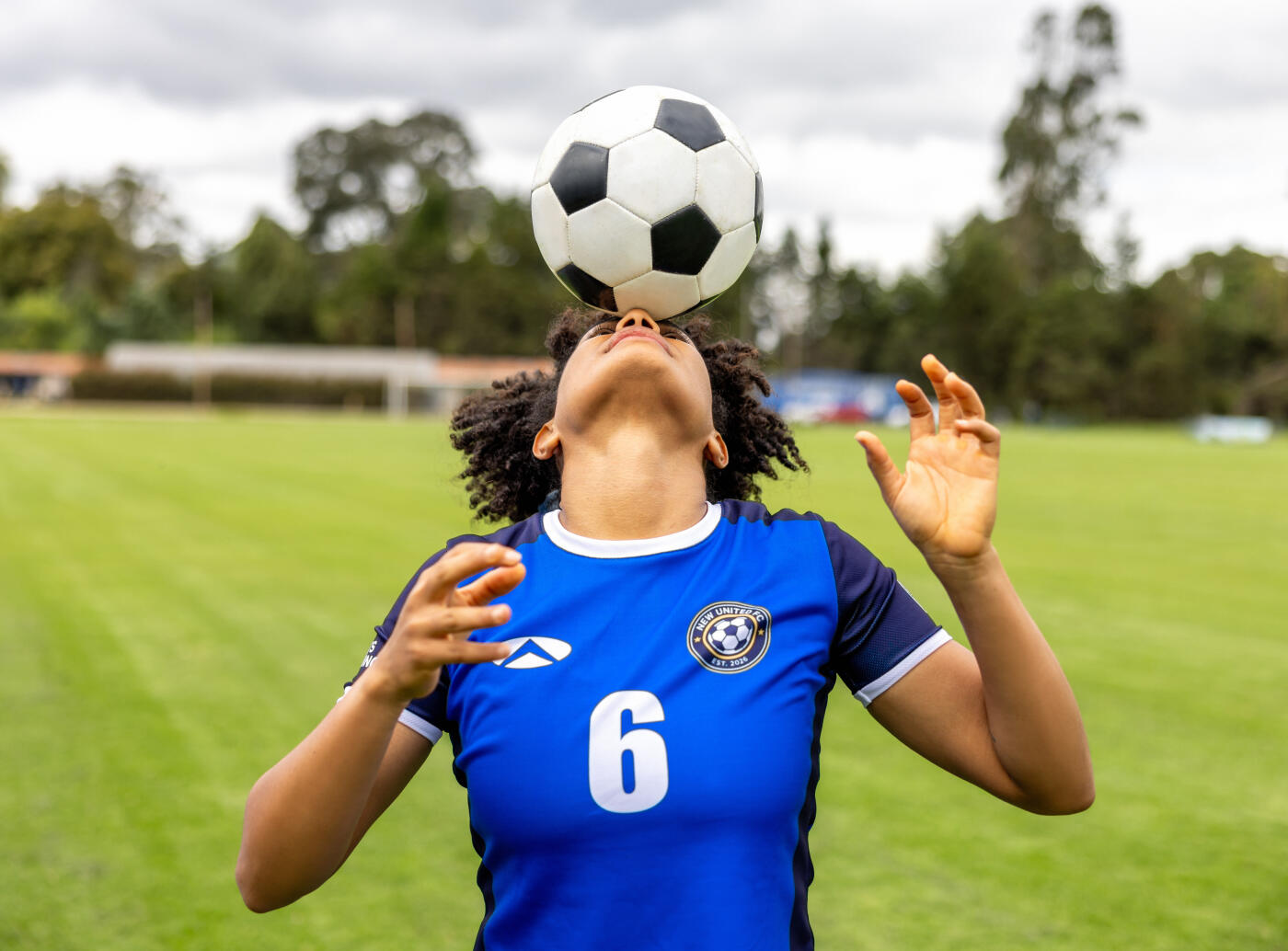 Portrait of a Latin American female football player controlling the ball with her head while training - sports concepts