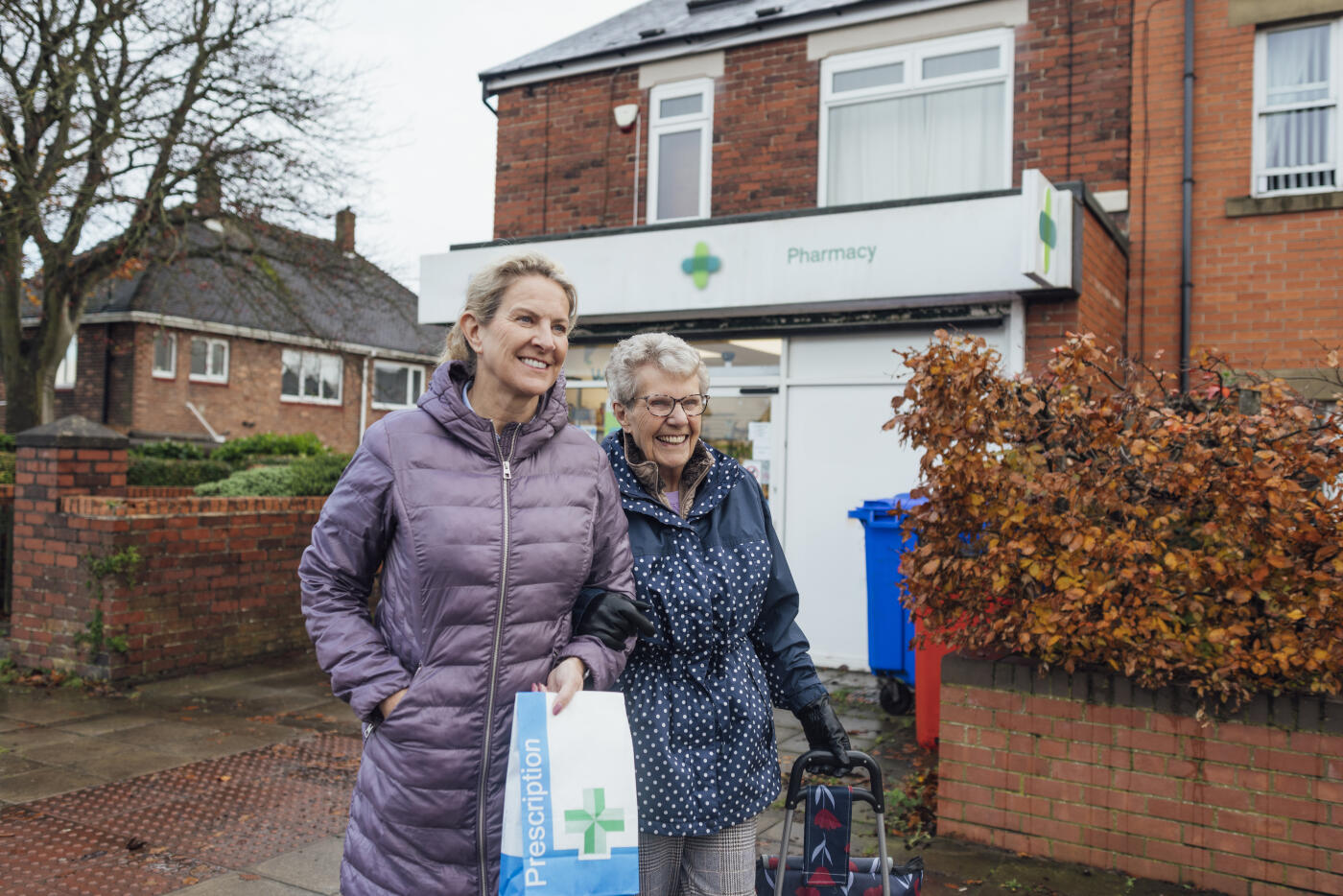 A mature woman out and about with her mother in Seghill, Northumberland. The senior woman has dementia and is arm in arm with her daughter for support and assistance as they walk on a footpath in town. They have just picked up the senior woman's prescription at the pharmacy behind them.

Videos also available for similar scenario.