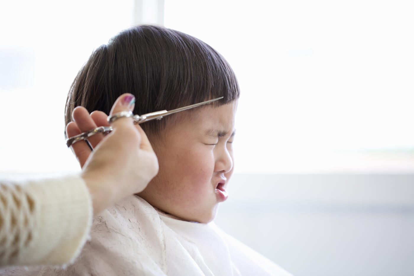 A boy is patient with having his hair cut in a beauty salon.