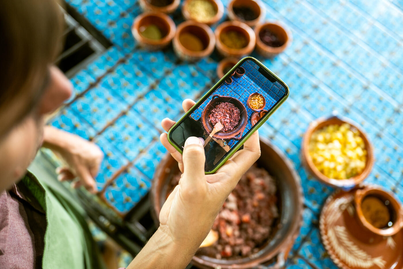 Overhead shot of hands holding a phone to capture Mexican feast being cooked in a Mexican Cooking class.