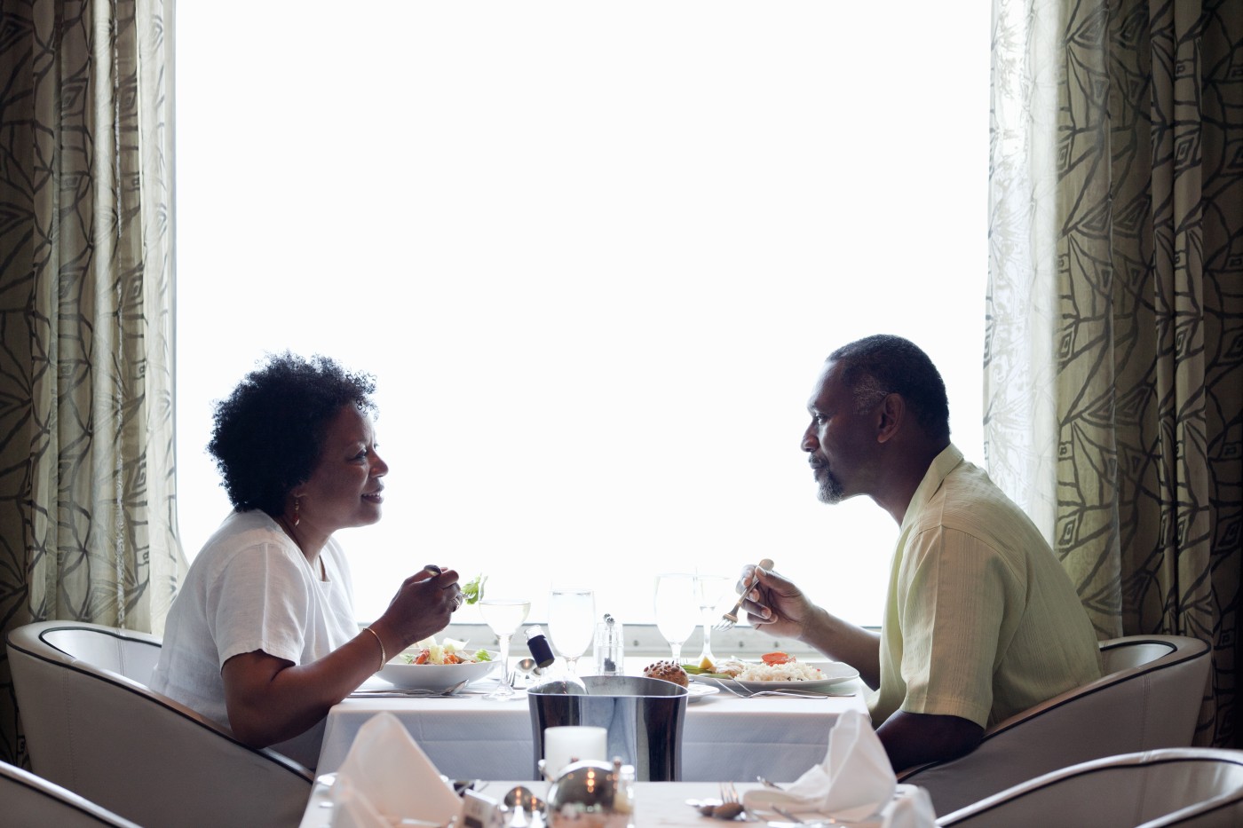 Mature African American couple with forks in each hand, about to eat dinner while vacationing on a cruise.