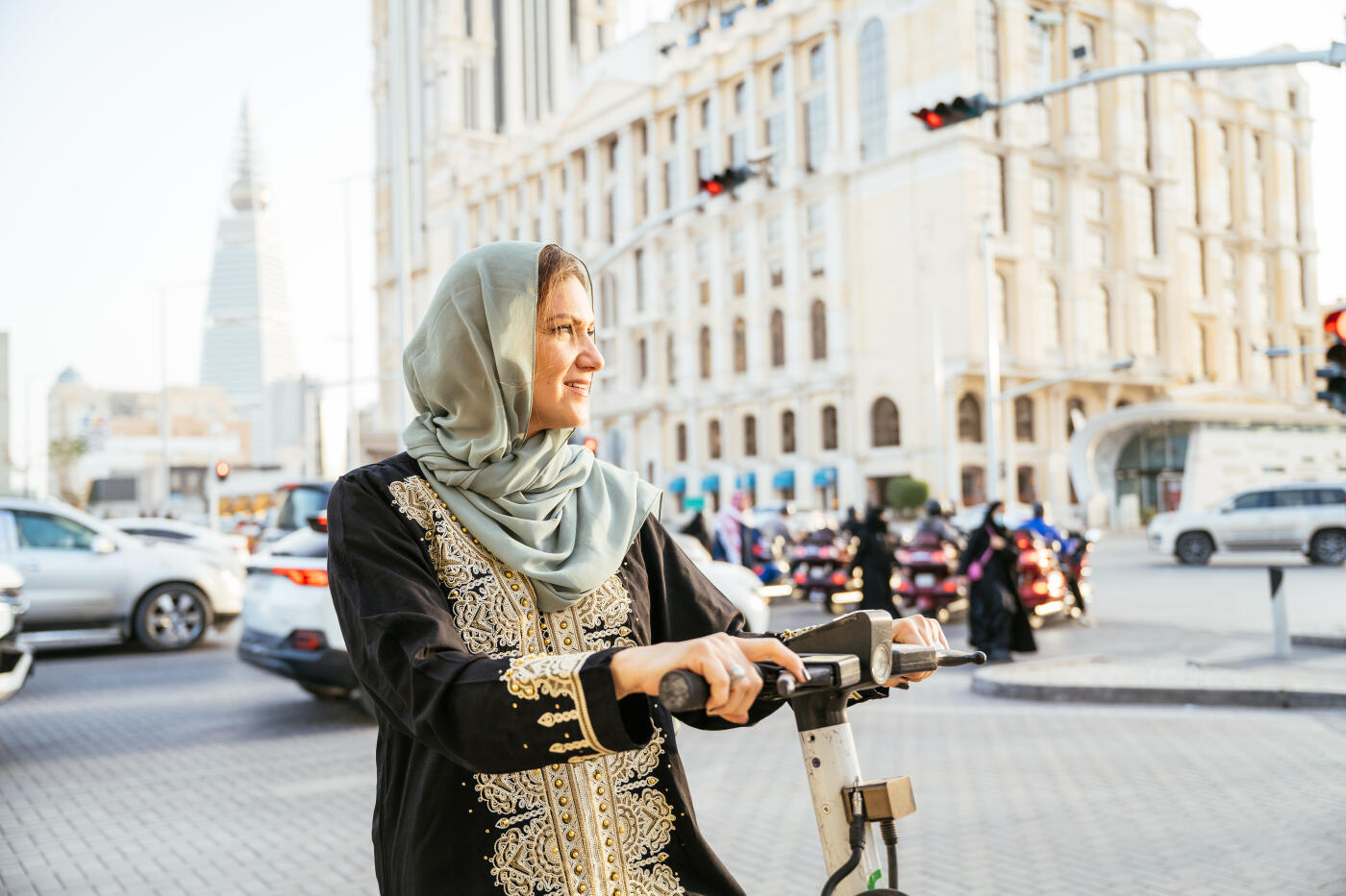 Smiling Arabic woman using electric scooter in the downtown