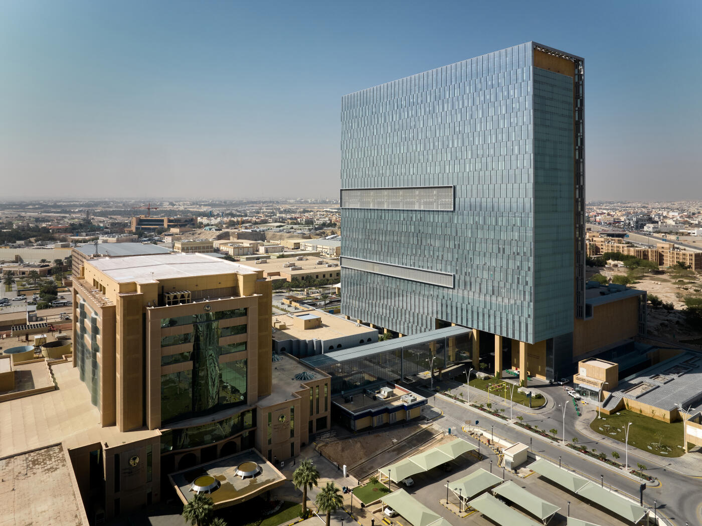 This captivating aerial photograph showcases the King Faisal Specialist Hospital Research Centre in Riyadh, Saudi Arabia. The image features the hospital's impressive modern tower, a gleaming symbol of set against a backdrop of lush green lawns and palm trees. The contrast between the contemporary architecture and the natural landscape creates a sense of tranquility and healing, reflecting the hospital's mission to provide world-class care in a compassionate environment.