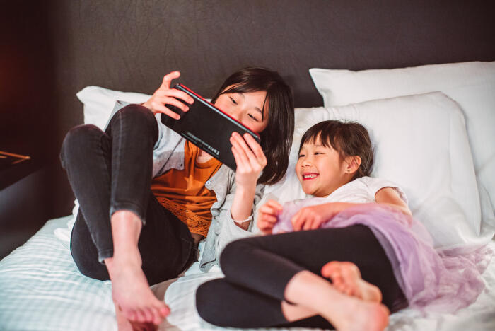 Young cheerful sibling enjoying quality time with video games in hotel room